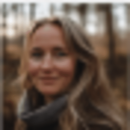 Een vrouw met lang golvend haar en een sjaal glimlacht zachtjes naar buiten. Haar kalme zelfvertrouwen en hoge slagingskans schijnen door tegen een vage achtergrond van bomen en bruine tinten.