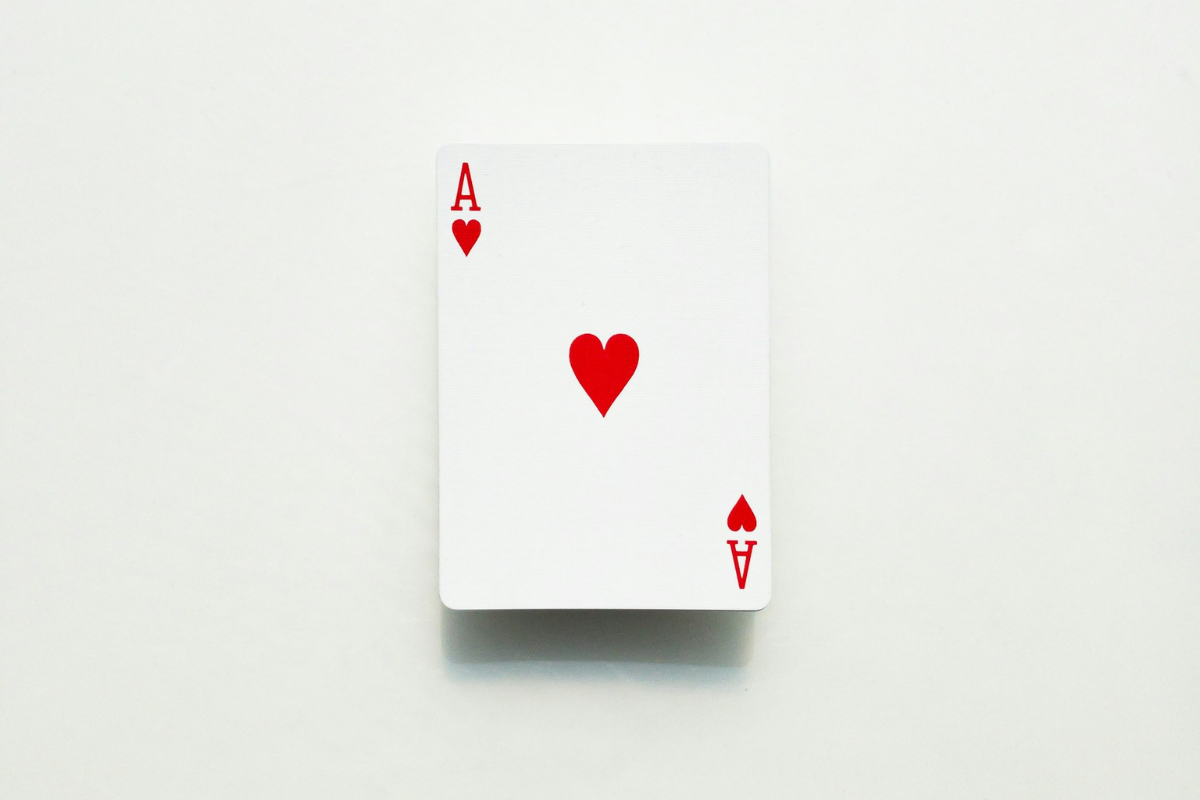 Een enkele speelkaart, de harten aas, ligt open op een effen witte achtergrond en symboliseert EQ en emotioneel inzicht.