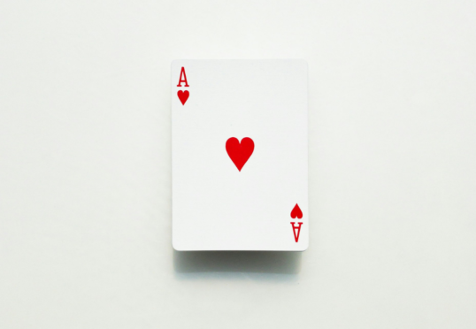 Een enkele speelkaart, de harten aas, ligt open op een effen witte achtergrond en symboliseert EQ en emotioneel inzicht.