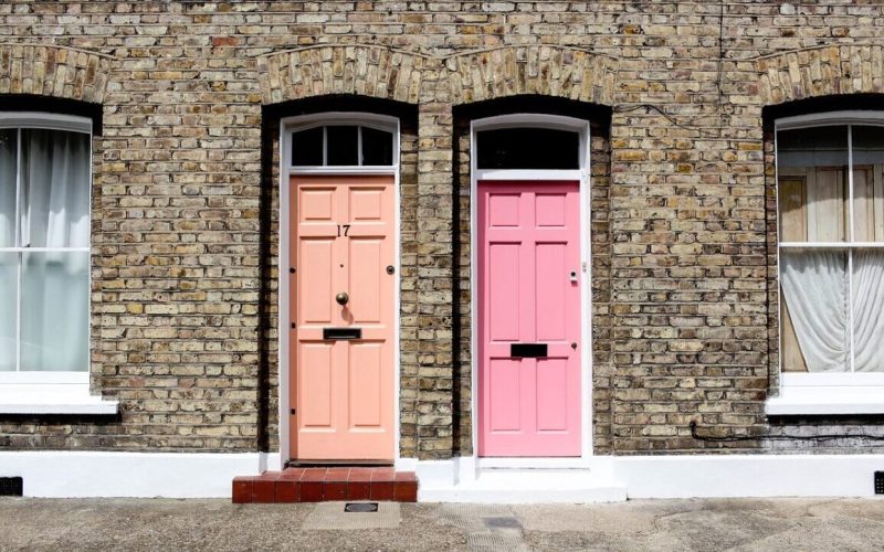 Twee naburige bakstenen rijtjeshuizen, perfect voor LAT-wonen, hebben gewelfde ramen en twee voordeuren - een perzikkleurig met het nummer 17, de andere roze - elk geaccentueerd door kraakheldere witte sierlijsten rond de deuren en ramen.