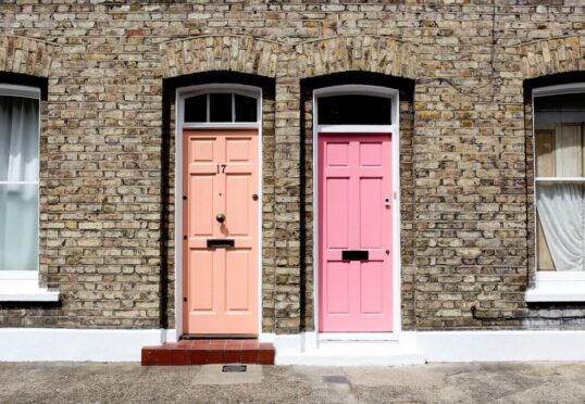 Twee naburige bakstenen rijtjeshuizen, perfect voor LAT-wonen, hebben gewelfde ramen en twee voordeuren - een perzikkleurig met het nummer 17, de andere roze - elk geaccentueerd door kraakheldere witte sierlijsten rond de deuren en ramen.