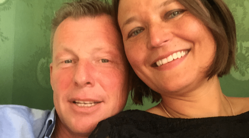 verhaal-4 Een man en een vrouw glimlachen naar de camera terwijl ze een selfie maken. De man, met kort, lichtgekleurd haar, draagt een lichtblauw overhemd. De vrouw heeft bruin haar tot op haar schouders en draagt een zwarte top. Ze lijken samen gelukkig en laten mogelijk hun succes zien via datingbureau-diensten, tegen een achtergrond met een groen patroon.